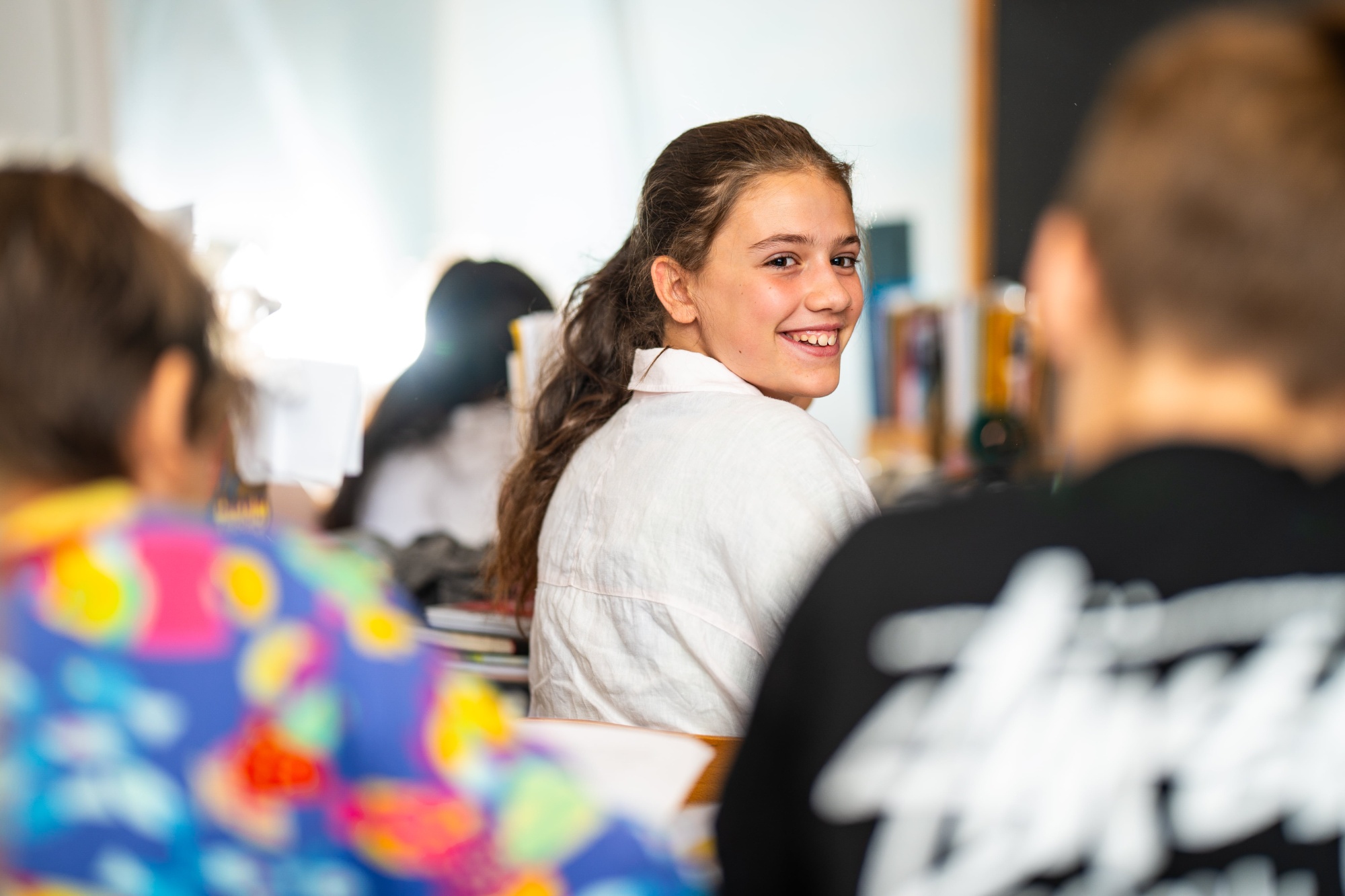 student turning in chair to smile at camera in classroom 