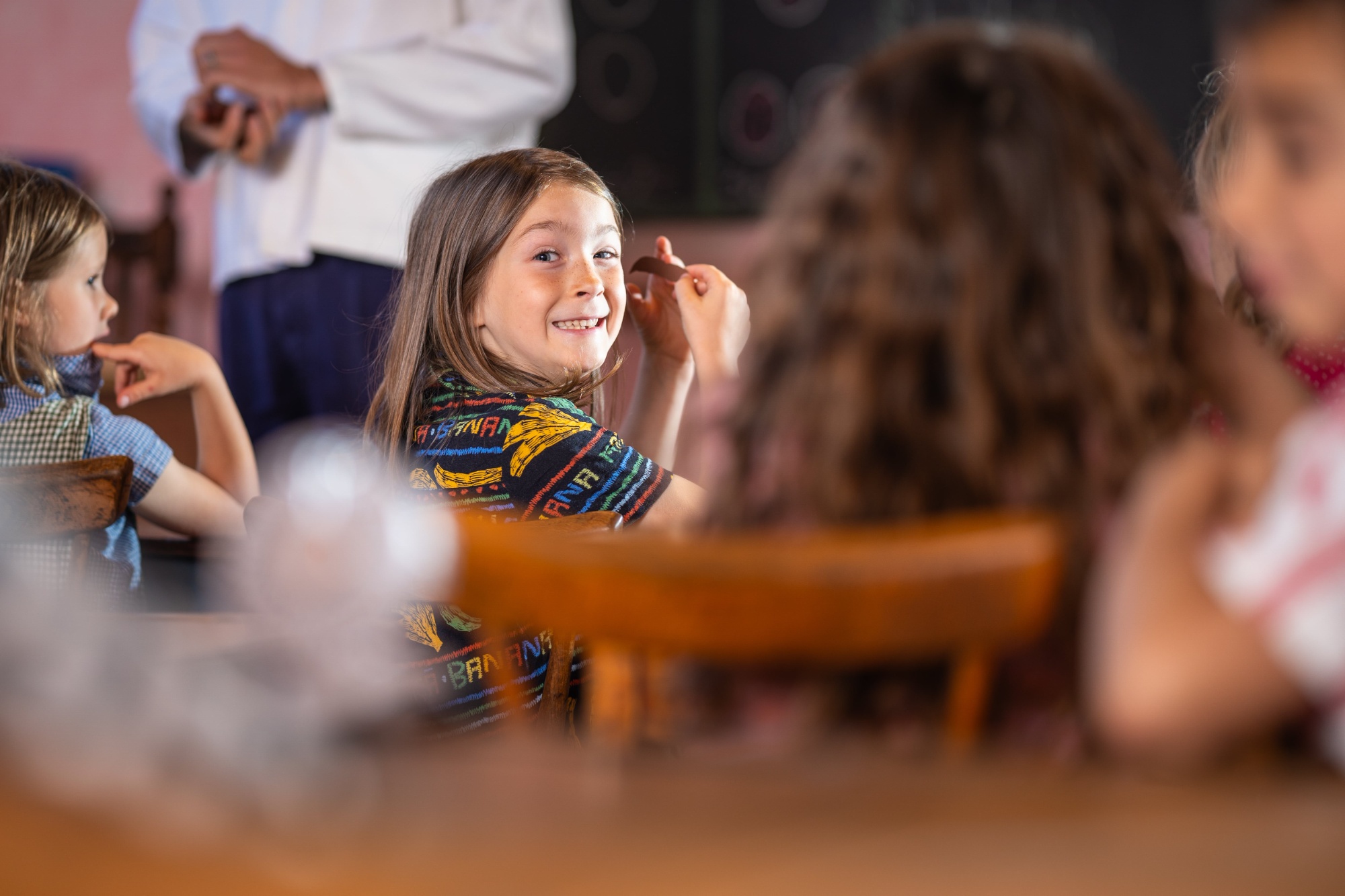 smiling child turning around in chair at front of class